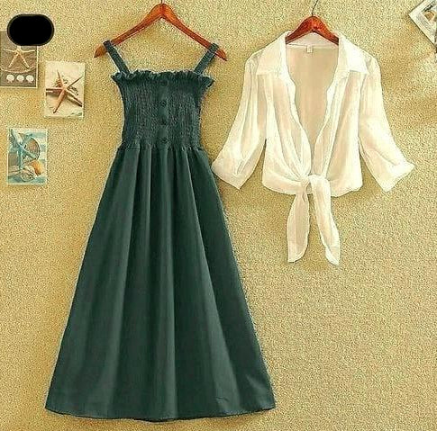 Green dress and white blouse on hangers against a textured beige wall.