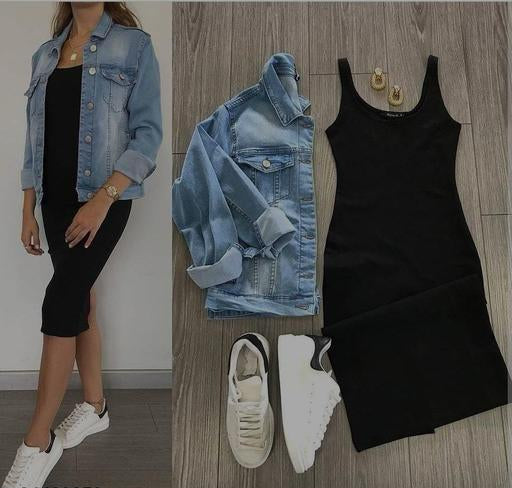 Woman wearing a denim jacket, black dress, and white sneakers on a wooden floor.